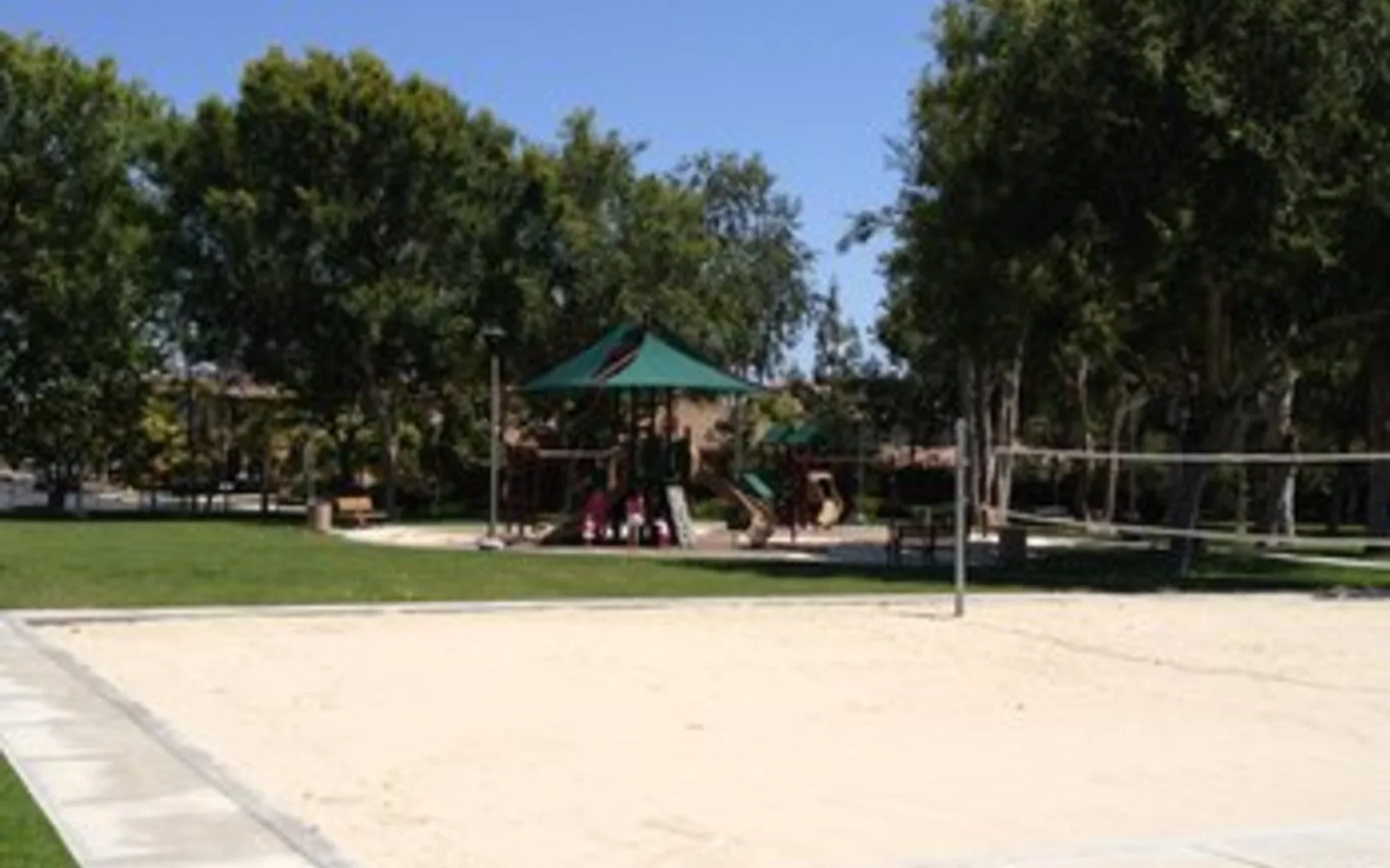 A park with green grass and trees in a suburban Orange County community, showing family-friendly recreational spaces